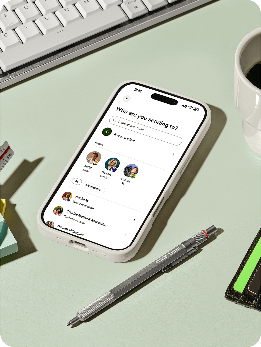 A smartphone on a desk next to office items, displaying a "Who are you sending to?" interface.